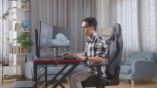 Side View Of Asian Male Automotive Designer Working On 3D Model Of Ev Car On The Desktop Computers At Home
