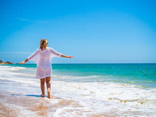 Beautiful woman walking on sunny beach
