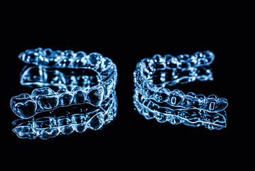 Invisible dental teeth brackets tooth aligners on black background. Plastic braces dentistry...