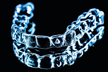 Invisible dental teeth brackets tooth aligners on black background. Plastic braces dentistry retainers to straighten teeth.