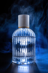 Presentation of perfume product with blue smoke. Beauty concept