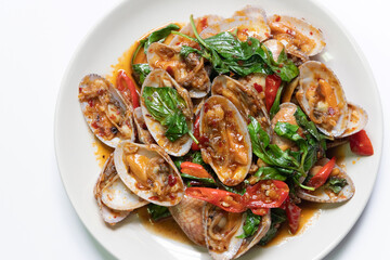 Stir-fried clams with chili paste and sweet basil on white plate. 