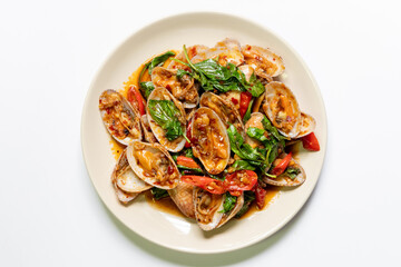 Stir-fried clams with chili paste and sweet basil on white plate. 
