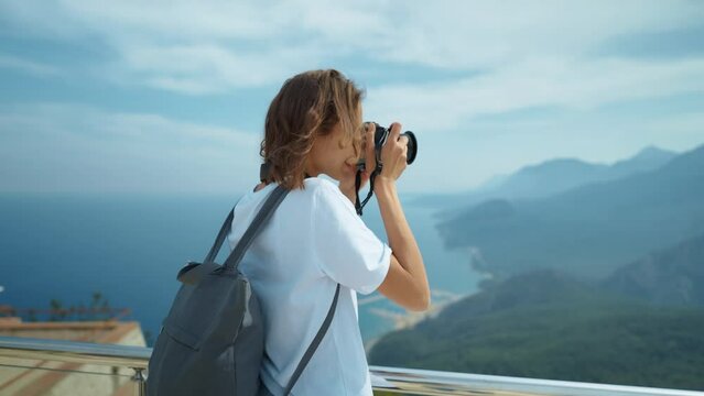 attractive woman hipster travel blogger takes photo on professional camera, viewpoint among mountains and blue sky, cableway destination. viewpoint of Tunektepe Teleferik, Antalya, Turkey