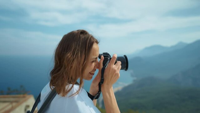 attractive woman hipster travel blogger takes photo on professional camera, viewpoint among mountains and blue sky, cableway destination. viewpoint of Tunektepe Teleferik, Antalya, Turkey