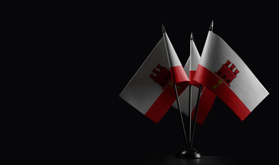 Small national flags of the Gibraltar on a black background