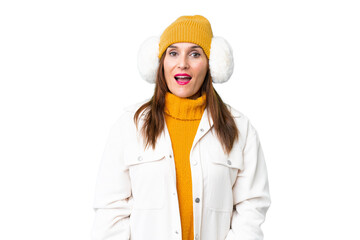 Middle age woman wearing winter muffs over isolated chroma key background with surprise facial expression