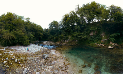 The Abhesi waterfall, couple tourists man and woman, a mountain river with clear water. the stones are turned by the stream. Tourist place for rest and swimming. Aerial view. western Georgia