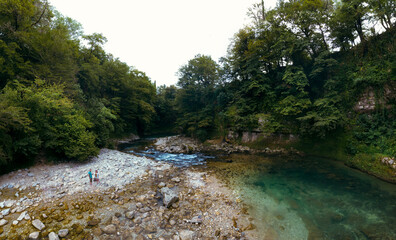 The Abhesi waterfall, couple tourists man and woman, a mountain river with clear water. the stones are turned by the stream. Tourist place for rest and swimming. Aerial view. western Georgia