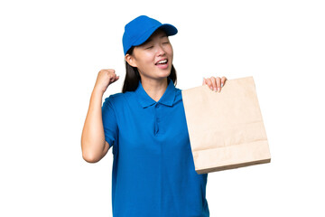Young Asian woman taking a bag of takeaway food over isolated background celebrating a victory