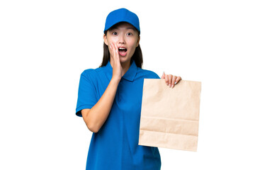 Young Asian woman taking a bag of takeaway food over isolated background with surprise and shocked facial expression