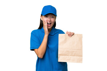 Young Asian woman taking a bag of takeaway food over isolated background shouting with mouth wide open