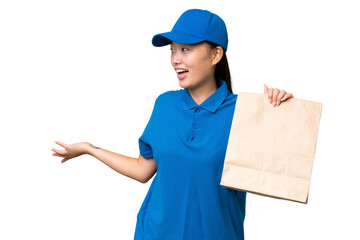 Young Asian woman taking a bag of takeaway food over isolated background with surprise expression while looking side