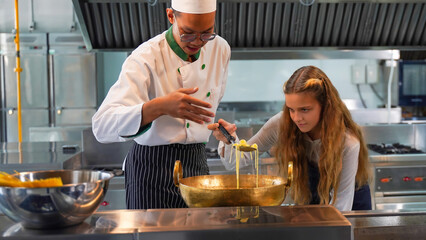 Chef teacher teaches cooking to the group children in class kitchen room.  Chef preparing student...