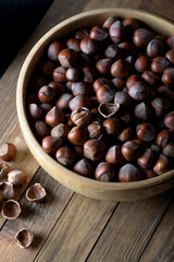 Hazelnut in a wooden bowl n a wooden background in rustic style. Raw hazelnuts. 