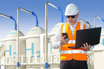 Hydrogen power plant builder. Man with laptop near tanks H2. Getting electric current from hydrogen. Man in orange vest works on electric station. Sustainable technology. Green fuel concept