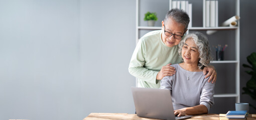 Mature old couple spending their time together using laptop computer, having a great time in the living room.
