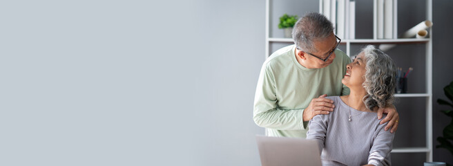 Mature old couple spending their time together using laptop computer, having a great time in the living room.