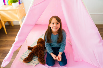 Portrait of a little girl playing in a pink teepee