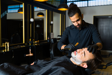 Fototapeta na wymiar Barber shaving the beard of a young man