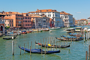 Picturesque view of Grand canal at Rialto Market with unique mixture of houses with different architecture style, gondolas, boats and water buses