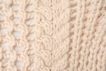 A fragment of beige knitted fabric, knitted from white sheep wool.