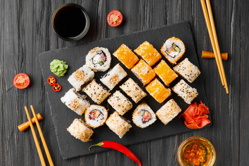 close up of sushi rolls on black tray top view
