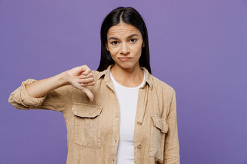 Young dissatisfied displeased sad latin woman wear light shirt casual clothes showing thumb down dislike gesture isolated on plain pastel purple color background studio portrait. Lifestyle concept.