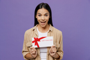 Young surprised shocked latin woman wearing light shirt casual clothes hold gift certificate coupon...