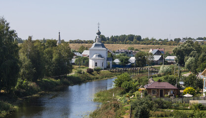 Panoramic view of the historical architecture of Suzdal in the Vladimir region among the green foliage of trees and Kamenka river on a sunny summer day and a space for copy