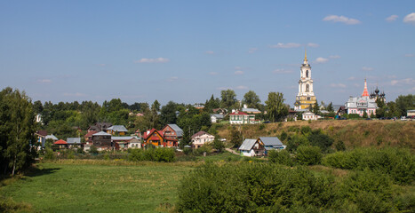 Beautiful panoramic landscape - the old town of Suzdal with a bell tower and historical architecture among green trees and grass on a sunny summer day and a space to copy