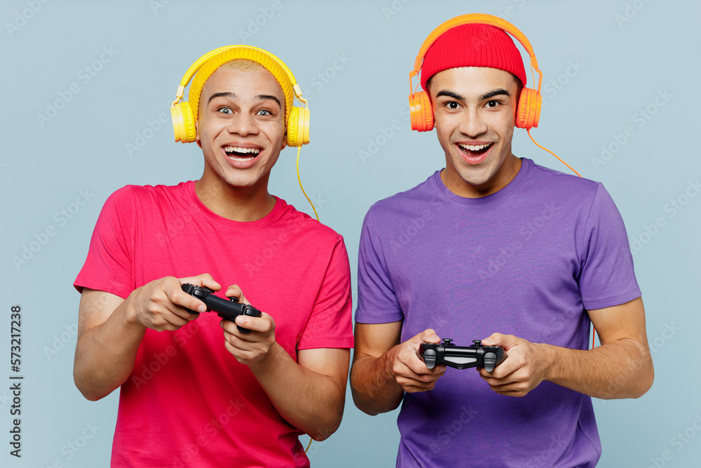 Wall mural young exited cool couple two friends men wear casual clothes headphones together hold in hand play p