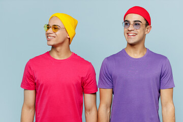 Young smiling happy fun cheerful shocked fun stylish cheerful fun couple two friends men wear casual clothes glasses together looking asidemisolated on pastel plain light blue cyan background studio.