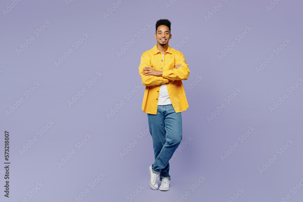 Poster Full body fun young man of African American ethnicity wear yellow shirt t-shirt hold hands crossed folded look camera isolated on plain pastel light purple background studio. People lifestyle concept.