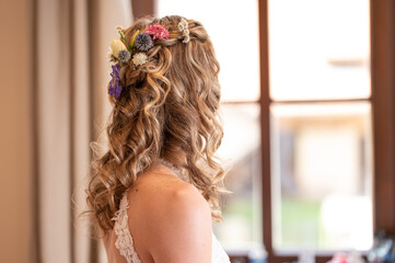 Naklejka premium bride with long curly hair looking from window