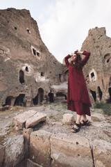 a beautiful girl sits and enjoys the view of the ancient architecture of the caves in Cappadocia.