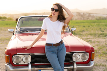 beautiful girl in retro style posing near vintage red cabriolet car.