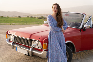 beautiful girl in retro style posing near vintage red cabriolet car.