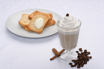 cup of coffee with milk covered with cream, toasted on the side