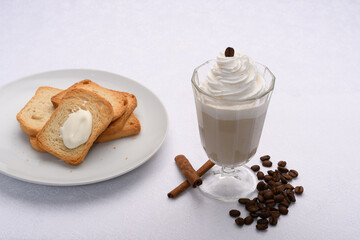 cup of coffee with milk covered with cream, toasted on the side
