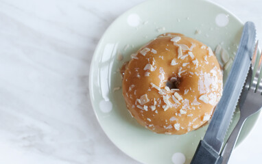 Sugar glazed donut on a plate. Sweet doughnut on table top view with space for text. Delicious dessert.