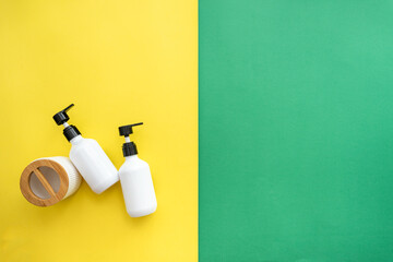 White Dispenser on green and yellow Background, top view, copy space. Blank plastic pump bottle for...