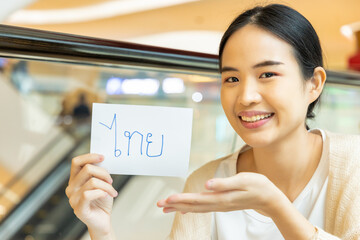 Smiling woman showing Thai vocab flash card, concept of southeast asian foreign language learning