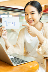 Smiling woman showing Thai vocab flash card, concept of southeast asian foreign language learning