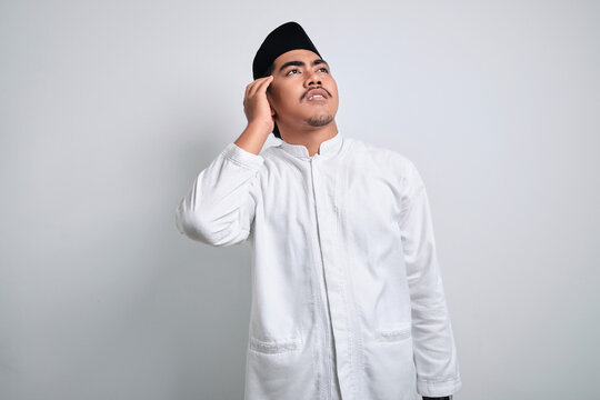 Asian muslim man in white clothes doing thinking gestue looking for any idea