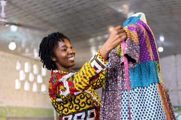 Happy West African woman dressmaker in her fashion studio