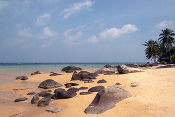 Tropical beach with stones and palm trees and a blue sea on Tioman Island in the South China Sea, belonging to Malaysia.