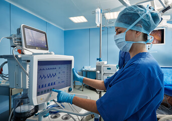 Nurse in operating room of hospital checking patient's vital signs while surgical operation....