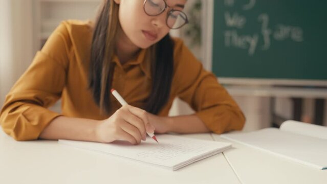 Young woman English teacher grading homework of her student, education