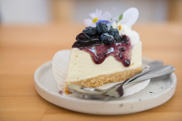 Cheesecake with fresh blueberries and flower decor on wooden table